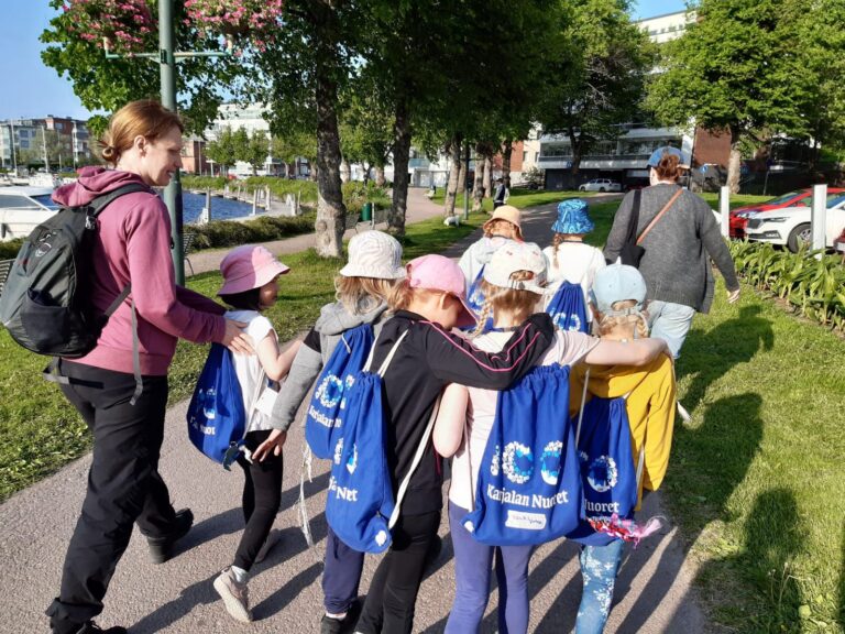 Ryhmä lapsia kävelee Karjalan Nuoret-reput selässään kädet toistensa hartioilla